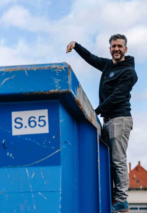 Matthias Schwarzer steht an einem Container und zeigt mit dem Finger in den Container rein