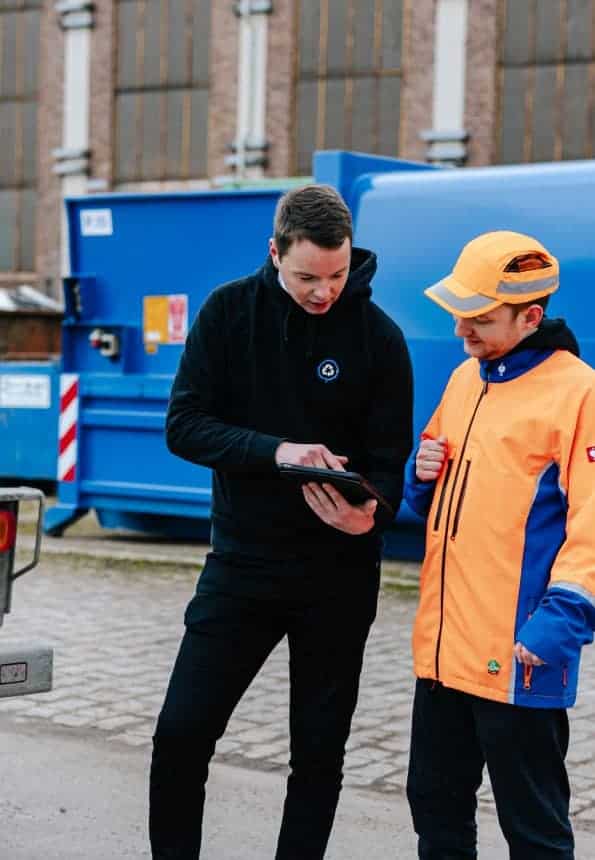 Zwei Männer unterhalten sich, im Hintergrund Abfallcontainer